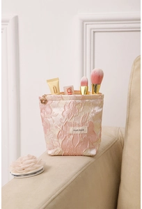 Detail of pink floral jacquard makeup bag with embossed flower pattern and woven brand label