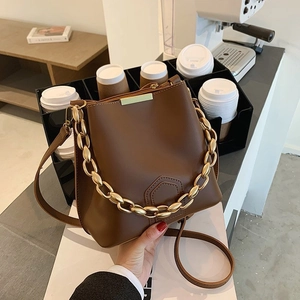Retro deep brown bucket bag with gold chain strap in a stylish cafe lifestyle setting
