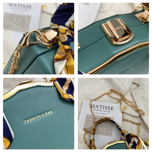 Detail of dark green leather box bag with gold hardware and silk scarf handle