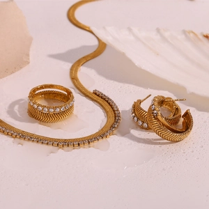 Close-up of 18K gold plated herringbone chain and zircon jewelry set on white surface