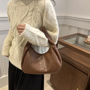 Borsa hobo marrone intrecciata con manico annodato indossata da una modella con stile