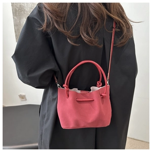 Detail showing the red pleated bucket bag with knotted handle on a black coat back view