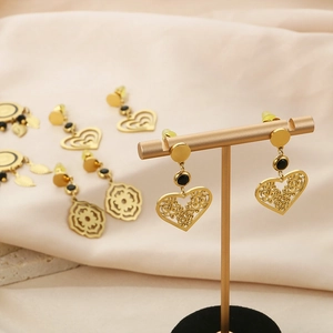 Détail de boucles d'oreilles cœur en acier titane doré sur un support en T pro