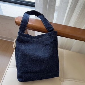Detail of dark blue denim bag with colorful speckles and simple wish side label