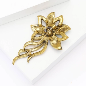 Macro detail of vintage gold flower brooch back with secure pin clasp and textured finish