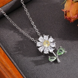 Gros plan du collier pendentif fleur avec zircons colorés dans un écrin à bijoux gris élégant