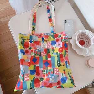 Sac fourre-tout en toile à fleurs colorées avec bretelles posé sur une table blanche