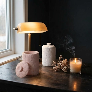 Detail view of embossed floral relief on resin storage jars in soft pink and ivory tones