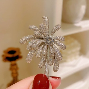 Close-up of elegant silver floral brooch with shimmering zircons and radial firework design
