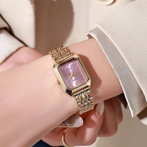Close-up of rectangular gold watch with purple sunray dial and steel mesh band on wrist