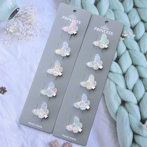 Detail shot of ten iridescent butterfly hair clips on a soft knit background