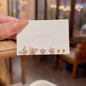 Detalle de tres pendientes dorados con circonitas en forma de mariposa y estrella