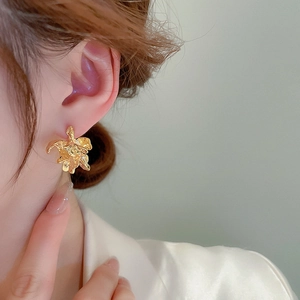Golden irregular flower earrings with hammered texture shown on model in close-up shot