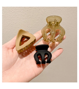 Detailed view of matte black and amber acrylic hair claws held in hand for styling