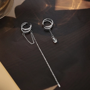 Detail of silver asymmetric ear cuffs with long tassel chains and crystal pendants