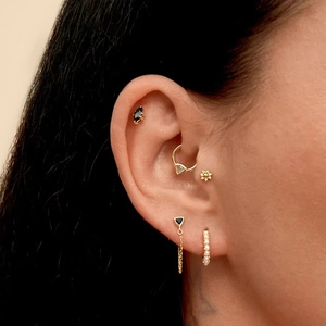 Close-up of geometric S925 silver cartilage hoops and triangle earrings on an ear