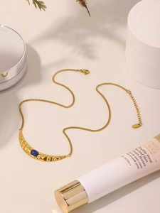 Detail of gold crescent moon necklace with hammered texture and blue stone inlay