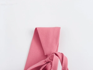 Détail des bretelles en tissu rose avec un design décoratif de nœud papillon noué