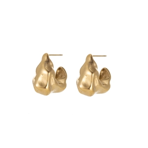 Detail of artistic irregular golden lava metal earrings with polished flower texture