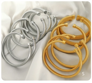 Close-up of gold and silver ribbed open bracelets on elegant white silk fabric