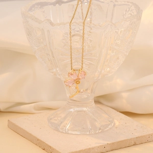 Fashionable gold three-petal flower necklace with pink gemstones on a glass display
