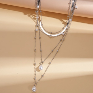 Close-up of silver multilayer necklace featuring faux pearl pendants on layered chains