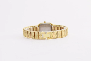 Detail of gold fashion watch with textured metal strap and secure silver case back