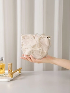 Bohemian off-white linen cosmetic bag with fringe details and a floral zipper puller
