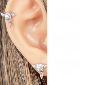Macro shot of silver heart wing earring with blue zircon and triangular crystal pendant
