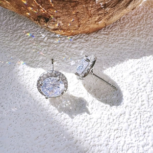 Vista macro di orecchini a lobo in zircone tondo argento con pavé su legno naturale
