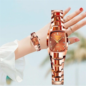 Detail of rose gold tonneau-shaped quartz watch with crystal indices and date window on wrist
