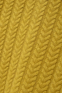 Macro detail of mustard yellow knit fabric with chunky cable stitch and herringbone pattern