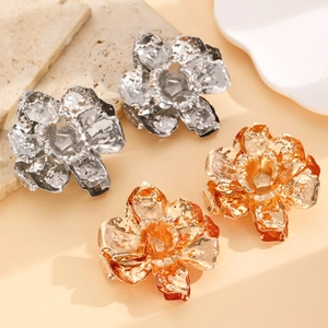 Detailed view of large gold and silver leaf earrings with hammered texture on stone base