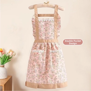 Détail du tablier floral en toile rose avec doubles poches et finitions dentelle