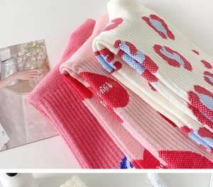 Close-up of pink and cream crew socks featuring blue and red leopard print patterns