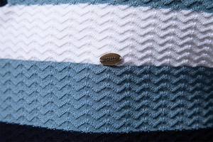 Macro shot of striped knit fabric texture with metal brand tag for men's polo shirt