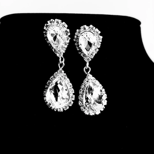 Macro view of silver teardrop crystal earrings with detailed halo setting on black stand