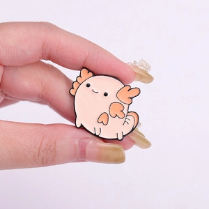 Cute pink axolotl enamel pin held in hand, cartoon aquatic animal metal brooch badge