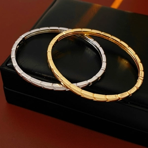 Detail view of gold and silver geometric cube bangles on a black leather jewelry box
