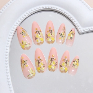 Almond press on nails with yellow floral patterns and pink base on white heart tray