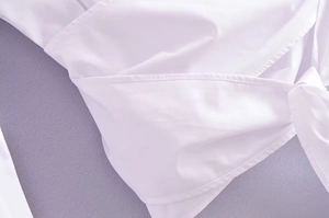 Gros plan sur le chemisier blanc croisé montrant la texture du tissu et les coutures