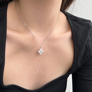 Detail shot of a sparkling silver four-leaf clover pendant with inlaid white zircons on a neck