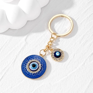 Détail macro du porte-clés Œil Mauvais doré avec émail bleu et strass brillants