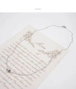 Macro view of silver cylinder necklace with small zircons on a decorative gift card