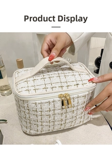Detail of tweed makeup bag showing woven texture, carry handle and gold double zippers