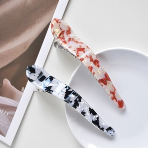 Flat lay view of two elegant acetate hair clips with marbled red and black patterns