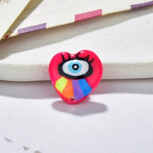 Macro shot of heart-shaped evil eye bead with colorful rainbow stripes for DIY jewelry