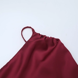 Close-up of wine red satin dress featuring thin straps and pleated neckline detail