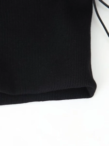 Close-up of black ribbed knit fabric showing detailed texture and stitching of the jacket