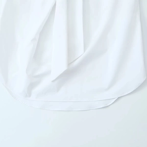 Detailed view of the clean white shirt hem with fine single-needle stitching and fabric texture